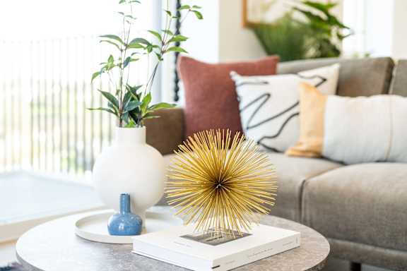 A table with a white vase, a blue vase, and a book on it.