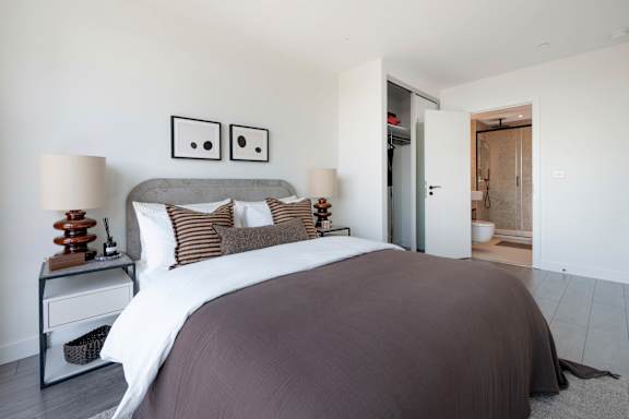 A bedroom with a large bed and two lamps.