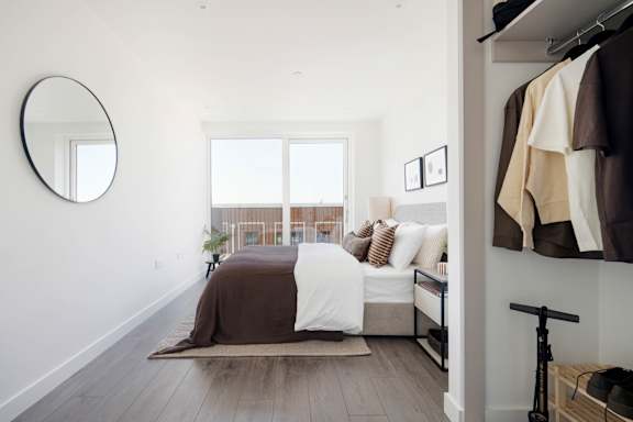A bedroom with a bed, a mirror, and a clothing rack.