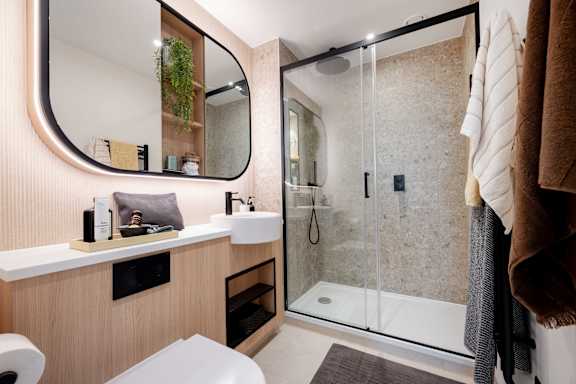 A bathroom with a mirror, sink, and shower.