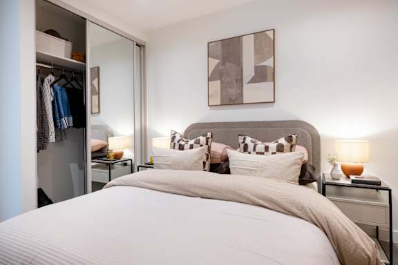 A bedroom with a large bed and a mirrored closet.
