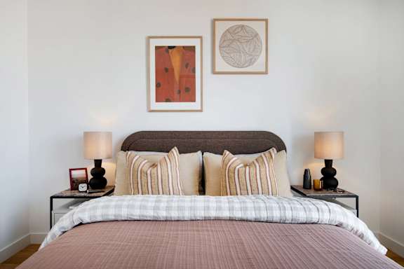 A bed with a brown headboard and striped pillows is in the image.