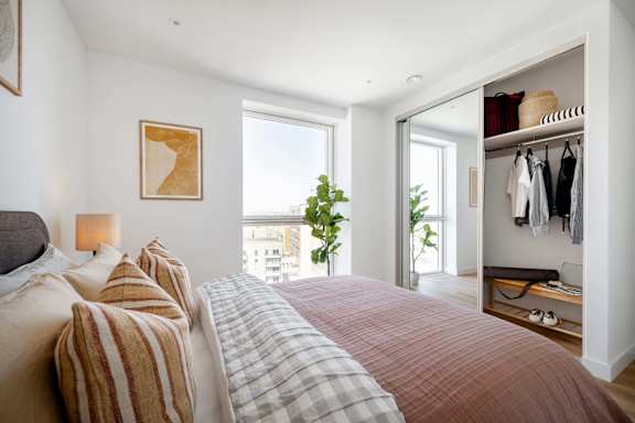 A bedroom with a large bed and a window overlooking a cityscape.