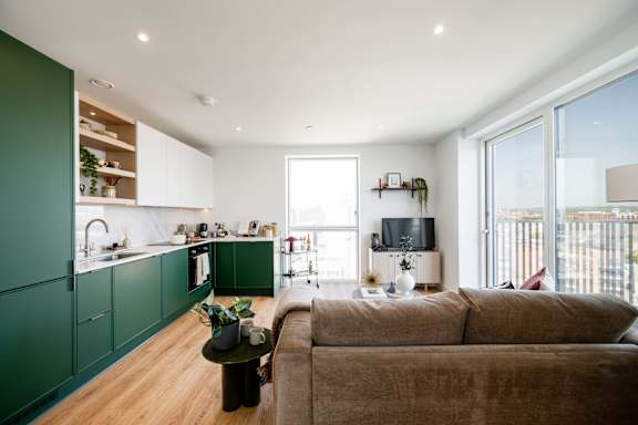 A modern living room with a brown couch and green cabinets.