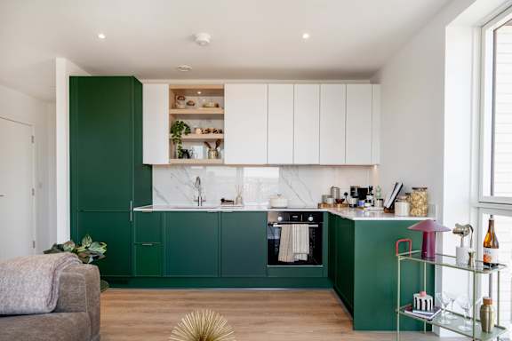 A kitchen with green cabinets and a white countertop.