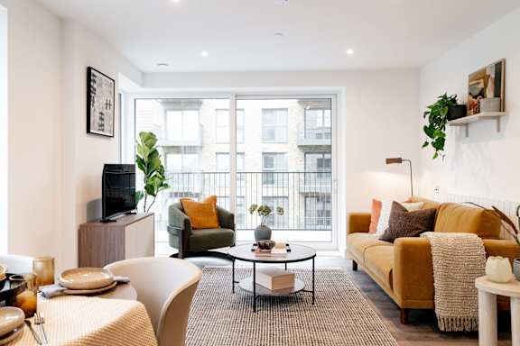 A living room with a yellow couch and a flat screen TV.