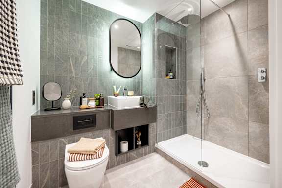 A bathroom with a toilet, sink, mirror, and shower.