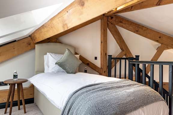 A bedroom with a bed and a wooden stool.