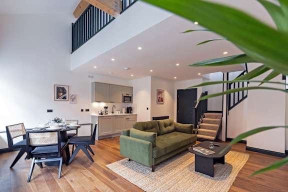 A living room with a green couch and a dining table.