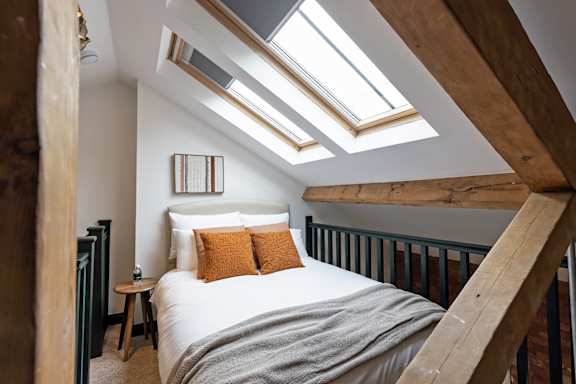 A bedroom with a bed, pillows, and skylights.