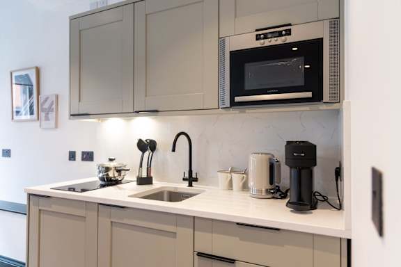A modern kitchen with a sink, microwave, and coffee maker.