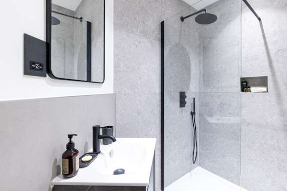 A modern bathroom with a white sink and a glass-enclosed shower.