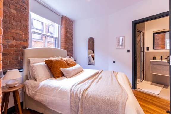 A bedroom with a bed, nightstand, and a mirror.