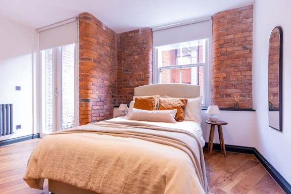 A bedroom with a large bed and a brick wall.