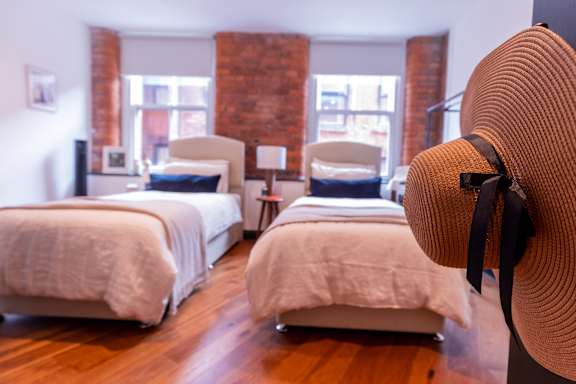 A room with two beds and a hat on a stand.