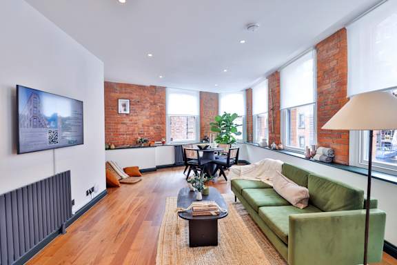 A living room with a green couch and a wooden floor.