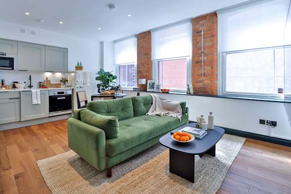 A green couch sits in a living room with a table in front of it.
