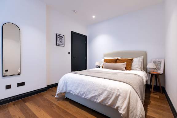 A bedroom with a large bed and a mirror on the wall.