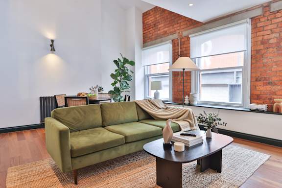 A green couch sits in a living room with a table in front of it.