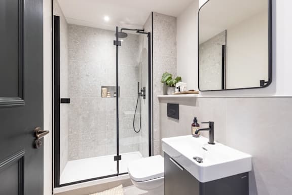 A modern bathroom with a walk-in shower and a white sink.