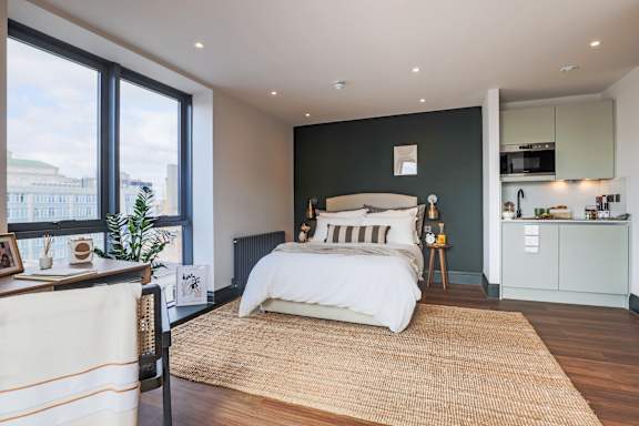A bedroom with a large bed and a window overlooking a cityscape.