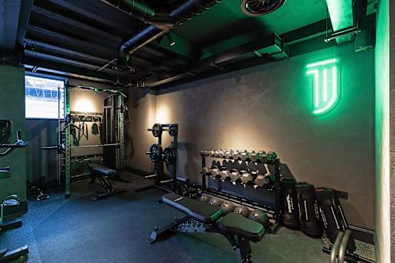 A gym with weights and a green neon sign.