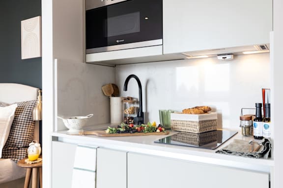 A modern kitchen with a microwave above the counter and various food items and utensils on the counter.