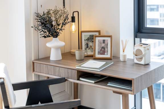 A desk with a vase, picture frames, and a lamp.