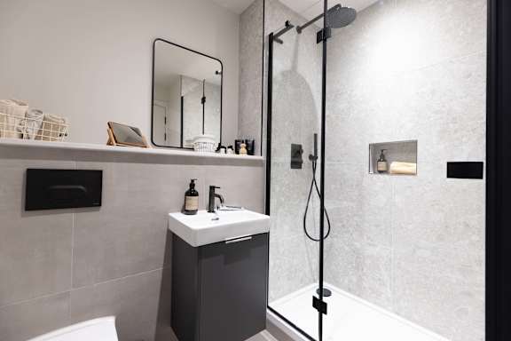 A bathroom with a white sink and a black shower.