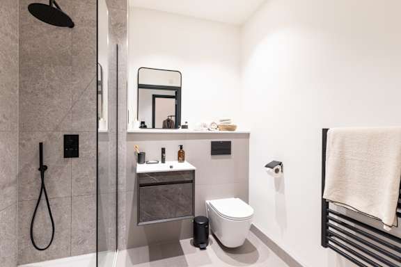 A bathroom with a toilet, sink, and mirror.