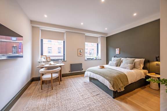 A bedroom with a bed, desk, and chair.