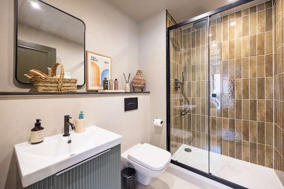 A bathroom with a white sink and toilet, a mirror, and a glass shower door.