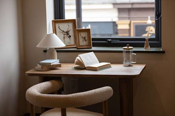 A desk with a lamp, a book, and a glass of water on it.
