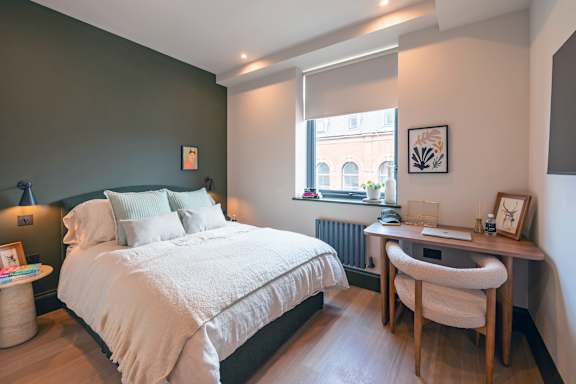 A bedroom with a bed, desk, and chair.