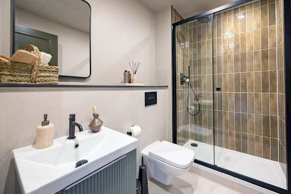 A bathroom with a white sink, toilet, and a glass shower stall.
