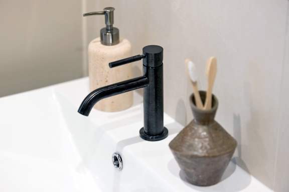 A black faucet is installed in a white sink.