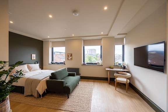 A bedroom with a bed, couch, and television.