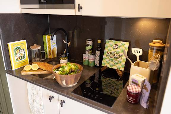 A kitchen counter with a bowl of salad, a cutting board with sliced lemons, and various kitchen items.