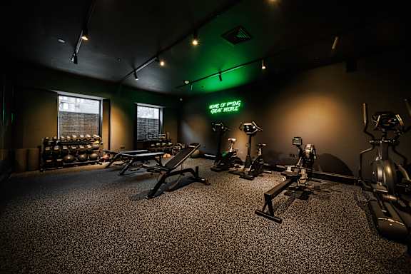 A gym with a green neon sign that says "WARM UP FITNESS".