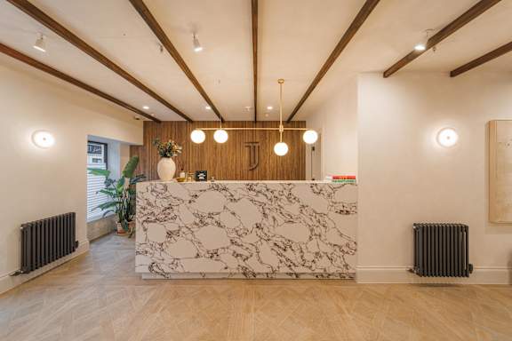 A reception area with a marble counter and wooden floors.
