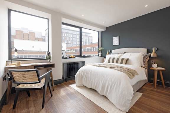 A bedroom with a large bed and a desk with a chair.
