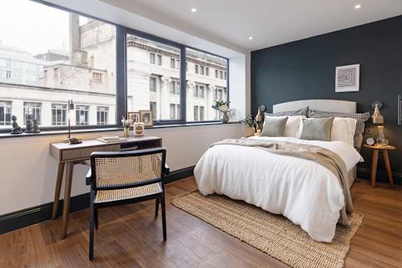 A bedroom with a large bed and a desk with a chair.
