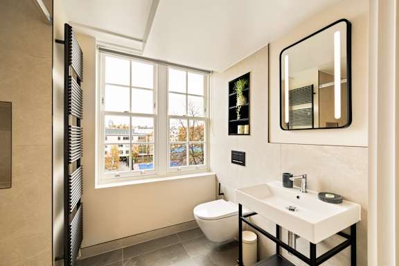 A bathroom with a toilet, sink, and mirror.