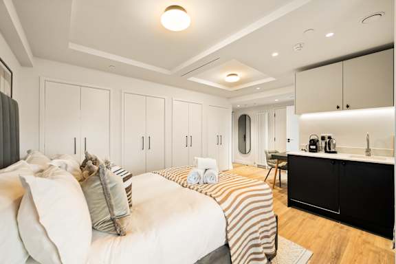 A bedroom with a bed, a vanity, and a chair.