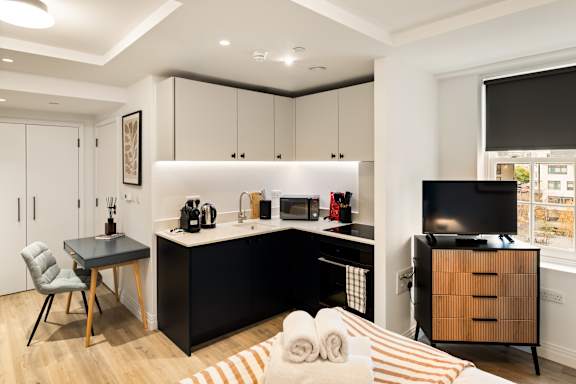 A modern kitchen with black countertops and white cabinets.