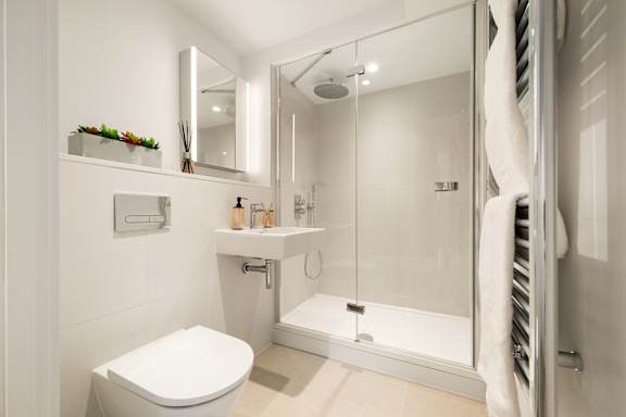 A white toilet is in a small bathroom with a walk-in shower.