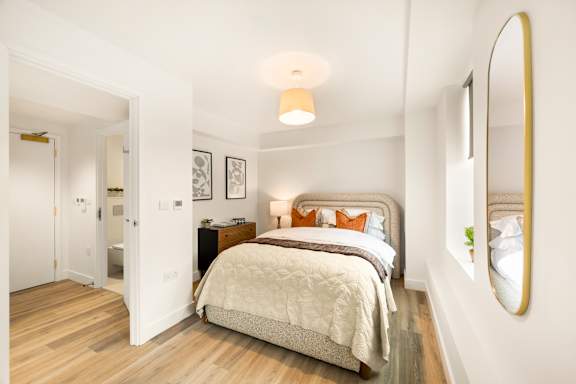 A bedroom with a bed, nightstand, and lamp.