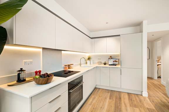A modern kitchen with white cabinets and a wooden floor.