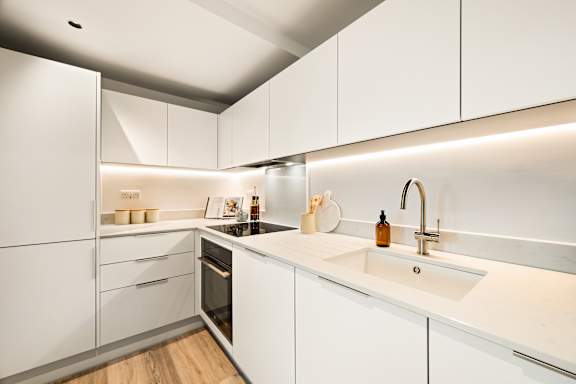 A modern kitchen with white cabinets and a wooden floor.