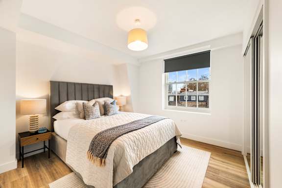 A bedroom with a large bed and a window with blinds.